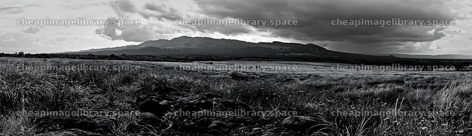 Kumamoto volcanic meadow with dark rock foreground and clouds – image library 14762x4268