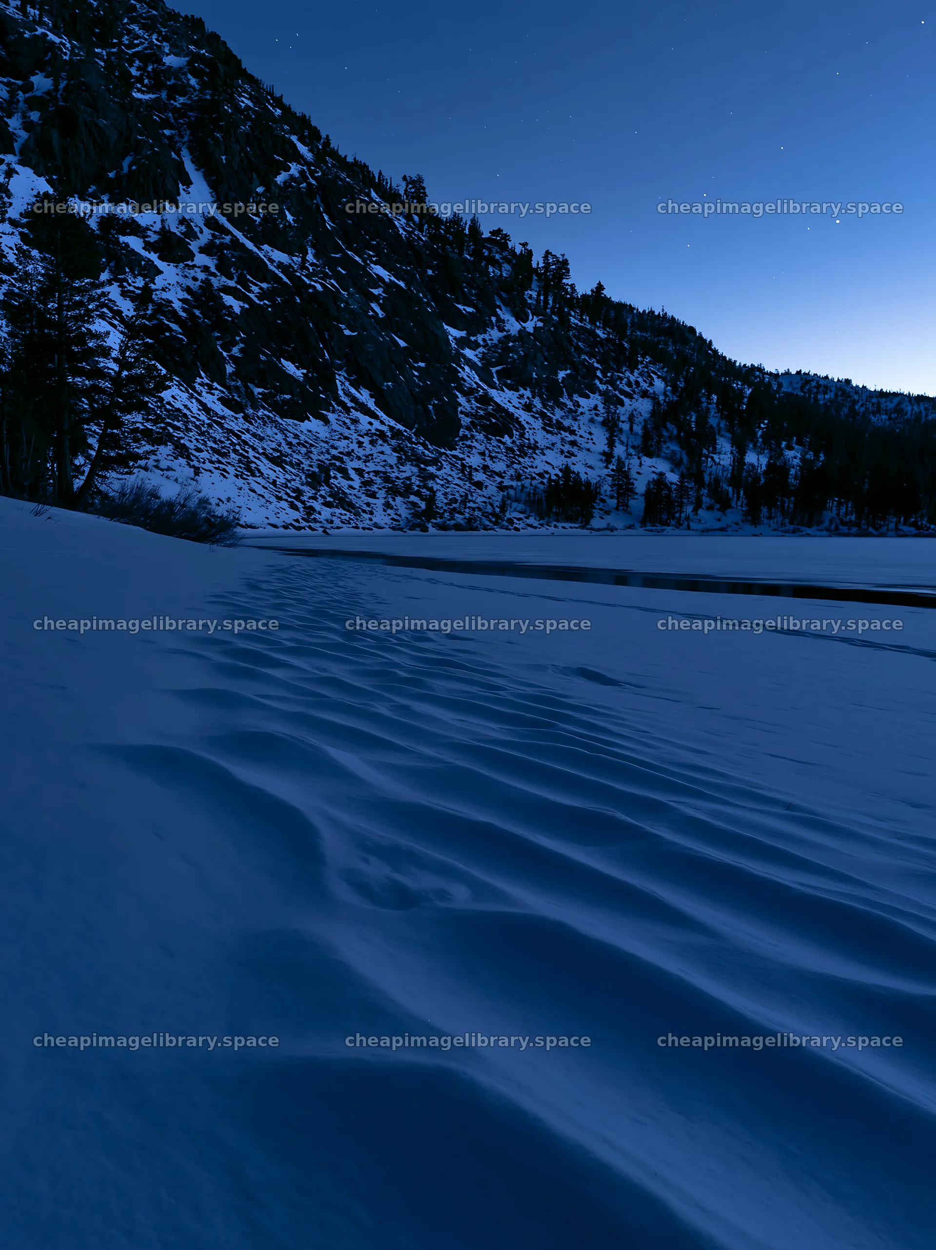 Snowy lakeside meadow under a blue sky at twilight – image library 6866x9174