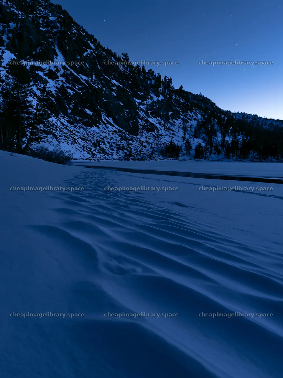 Snowy lakeside meadow under a blue sky at twilight – image library 6866x9174
