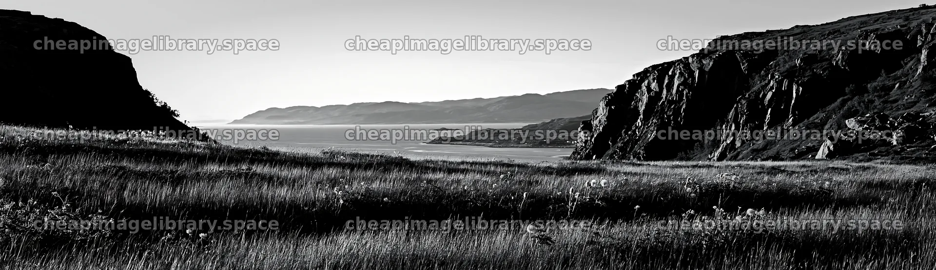 Meadow beneath crags with ocean view at sunset – image library 14762x4268