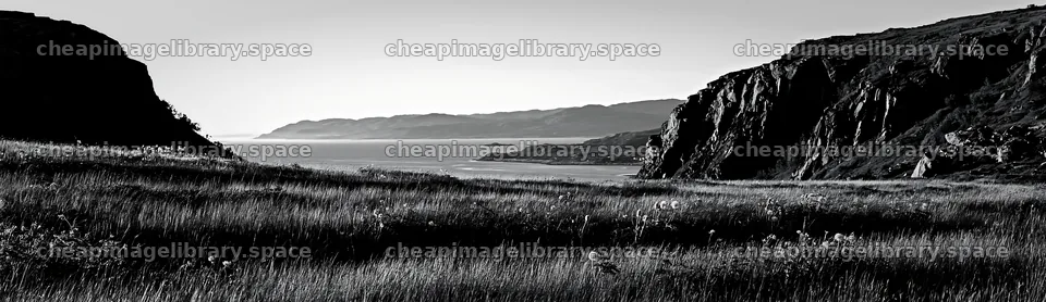 Meadow beneath crags with ocean view at sunset – image library 14762x4268