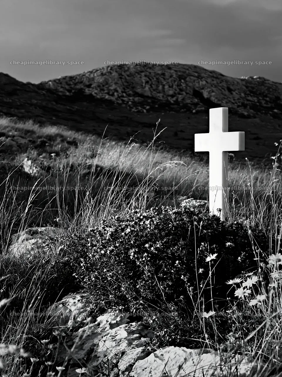 White Christian cross in a meadow surrounded by grass – image library 6866x9174