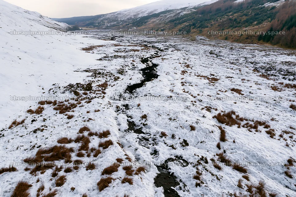 Aerial view of snowy meadow and valley in winter landscape – image library 9722x6480