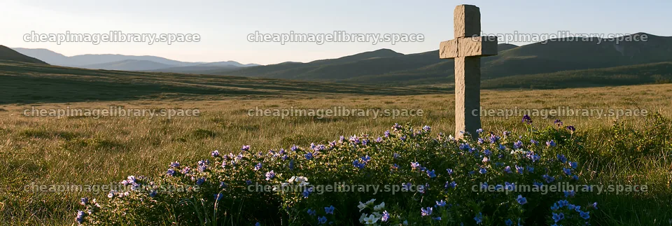 Simple cross in meadow with flowers and mountains in background – image library 13690x4602