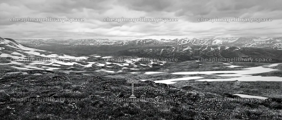Christian cross in winter mountain meadow in deep valley – image library 12124x5196